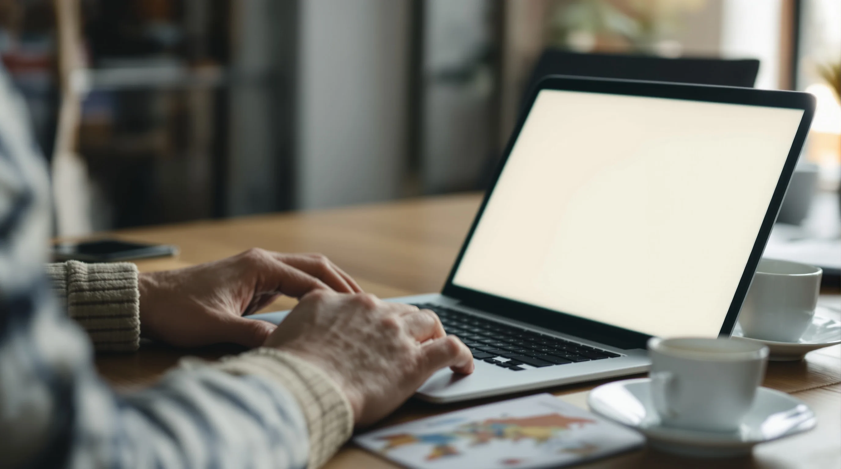 Over-the-shoulder view of a person at a laptop with the screen a soft glow, a passport beside it, illustrating the IRCC online TRV application from the UAE