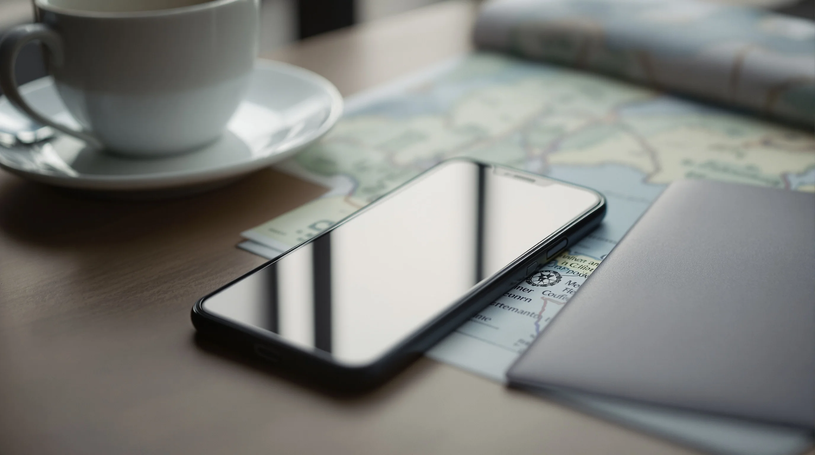 A smartphone with a soft glowing screen beside a passport and coffee on a table, illustrating a UK visa decision arriving by email